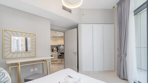 Habitació d'hotel moderna amb un llit ben fet, una taula amb cadira, un armari i vistes a la ciutat a través de grans finestres.