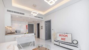 A modern living room with a dining area, a kitchen, and a sign that reads "BOOK ME". - Arjan Apartment Sleeps 3 With Private Balcony (Dubai)