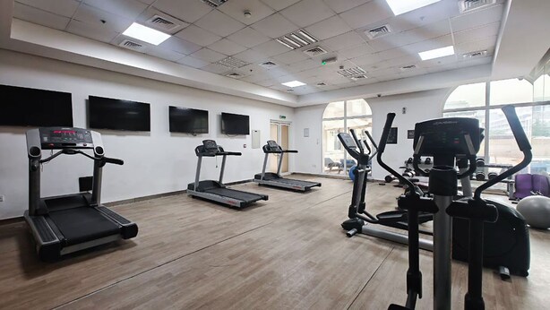 A gym with treadmills, elliptical machines, and weight equipment. - Cozy JVC Studio for 2 With Balcony (Dubai)