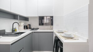 A modern kitchen with grey cabinets, a white countertop, and a built-in oven. - Cozy JVC Studio for 2 With Balcony (Dubai)