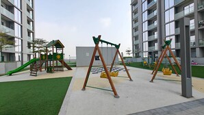 A playground with swings and a slide, surrounded by apartment buildings. - Chic 2 bed Apartment in Sobha Creek Vistas (Dubai)