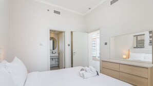 Une chambre d’hôtel avec un lit, une salle de bain avec un miroir et une fenêtre.
