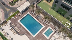 Vue aérienne d’un hôtel doté d’une grande piscine centrale, d’une piscine plus petite et d’espaces de détente en plein air.
