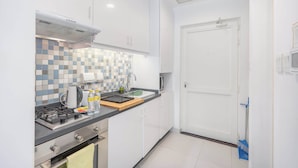 A compact kitchen with white cabinets, a tiled backsplash, a gas stove, and a small countertop. - Chic Studio in Palm Jumeirah Sleeps 2 With Balcony (Dubai)