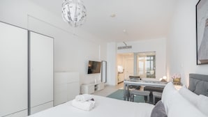 A modern hotel room with a large bed, a desk, and a dining area. - Chic Studio in Palm Jumeirah Sleeps 2 With Balcony (Dubai)