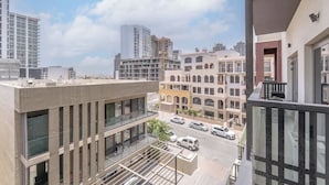 A high-rise building with multiple floors, large windows, and a view of a street with parked cars. - JVC Apartment That Sleeps 4 With a Great Pool (Dubai)