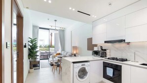 Une cuisine moderne équipée d’un lave-linge et d’un four intégrés, ainsi que d’un coin repas offrant une vue agréable.