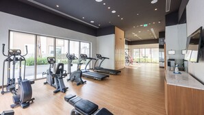 A modern gym with cardio machines, benches, and a reception area. - Dubai Creek Harbour Sleeps 4 With Swimming Pool (Dubai)
