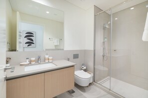 A modern bathroom with a glass shower enclosure, a white sink, and a toilet. - Dubai Creek Harbour Sleeps 4 With Swimming Pool (Dubai)