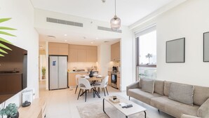 A modern living room with a sofa, coffee table, and dining area. - Dubai Creek Harbour Sleeps 4 With Swimming Pool (Dubai)
