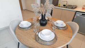A round dining table with a vase of dried pampas grass, white plates, and clear glasses. - Dubai Creek Harbour Sleeps 4 With Swimming Pool (Dubai)