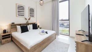 A modern hotel room with a large bed, bedside tables, a TV, and a view of the city through the window. - Dubai Creek Harbour Sleeps 4 With Swimming Pool (Dubai)