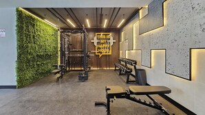 A modern gym with a green wall, weight racks, benches, and a motivational sign. - JVC Studio for 3 People With Swimming Pool (Dubai)