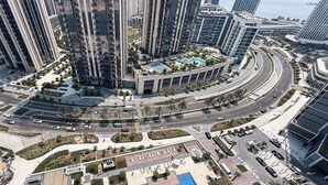 Een hoog appartementencomplex met een centrale binnentuin, een zwembad en een aangelegde tuin met palmbomen.