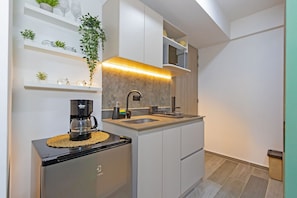Una cocina moderna con cafetera integrada, un fregadero y armarios blancos.