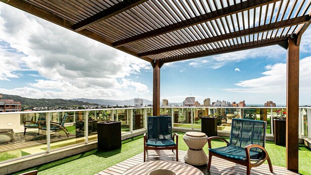 A rooftop terrace with wooden flooring, two wicker chairs, a round table, and a pergola. - Sophisticated fit With 3 Suites Jurere Les403 (Florianópolis)