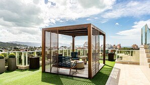 A rooftop terrace with a wooden pergola, seating area, and a view of the cityscape. - Sophisticated fit With 3 Suites Jurere Les403 (Florianópolis)