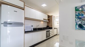 A modern kitchen with white cabinets, a built-in oven, and a stainless steel refrigerator.