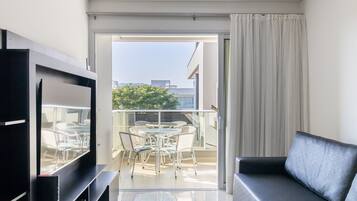 A modern living room with a flat-screen TV, a sofa, and a dining area with a table and chairs.