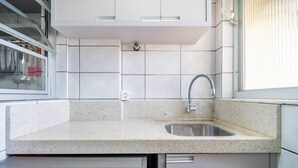 A kitchen with a granite countertop, a stainless steel sink, and white cabinets. - Apt w/ Balcony & BBQ 450m From the sea Reh0203 (Florianópolis)