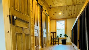 A wooden interior with a large sliding door, a chair, and a potted plant. - LE GARAGE 17 (Frelighsburg)