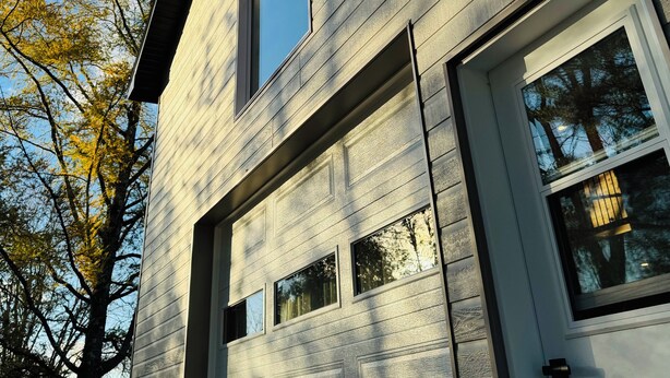 A modern building with a light-colored exterior, large windows, and a garage door. - LE GARAGE 17 (Frelighsburg)