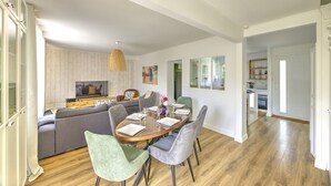 Ein modernes Wohnzimmer mit Esstisch, grauem Sofa und Fernseher.