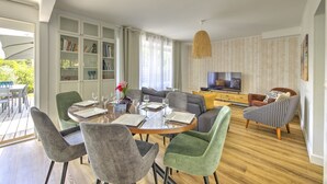 Ein modernes Wohnzimmer mit Essbereich, einem Fernseher und einer Bücherwand.