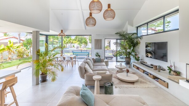 A modern living room with a large sofa, a TV, and a dining area with a bench and table.