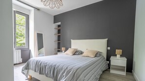 A modern bedroom with a bed, bedside tables, a window, and a wall-mounted shelf. - L’Escapade du Quai - Proche Gare (Pontivy)