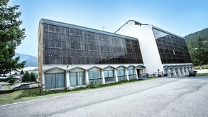 Un edificio moderno con grandes ventanales y techo plano, rodeado de un estacionamiento y zonas verdes.