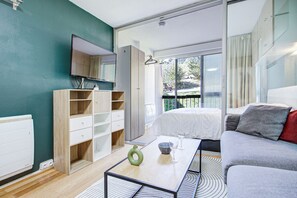 A modern living room with a sofa, a coffee table with a vase, and a television on the wall.