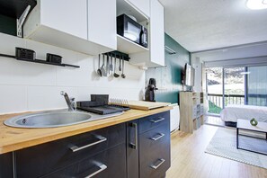 A modern kitchen with a sink, cabinets, and a coffee machine.