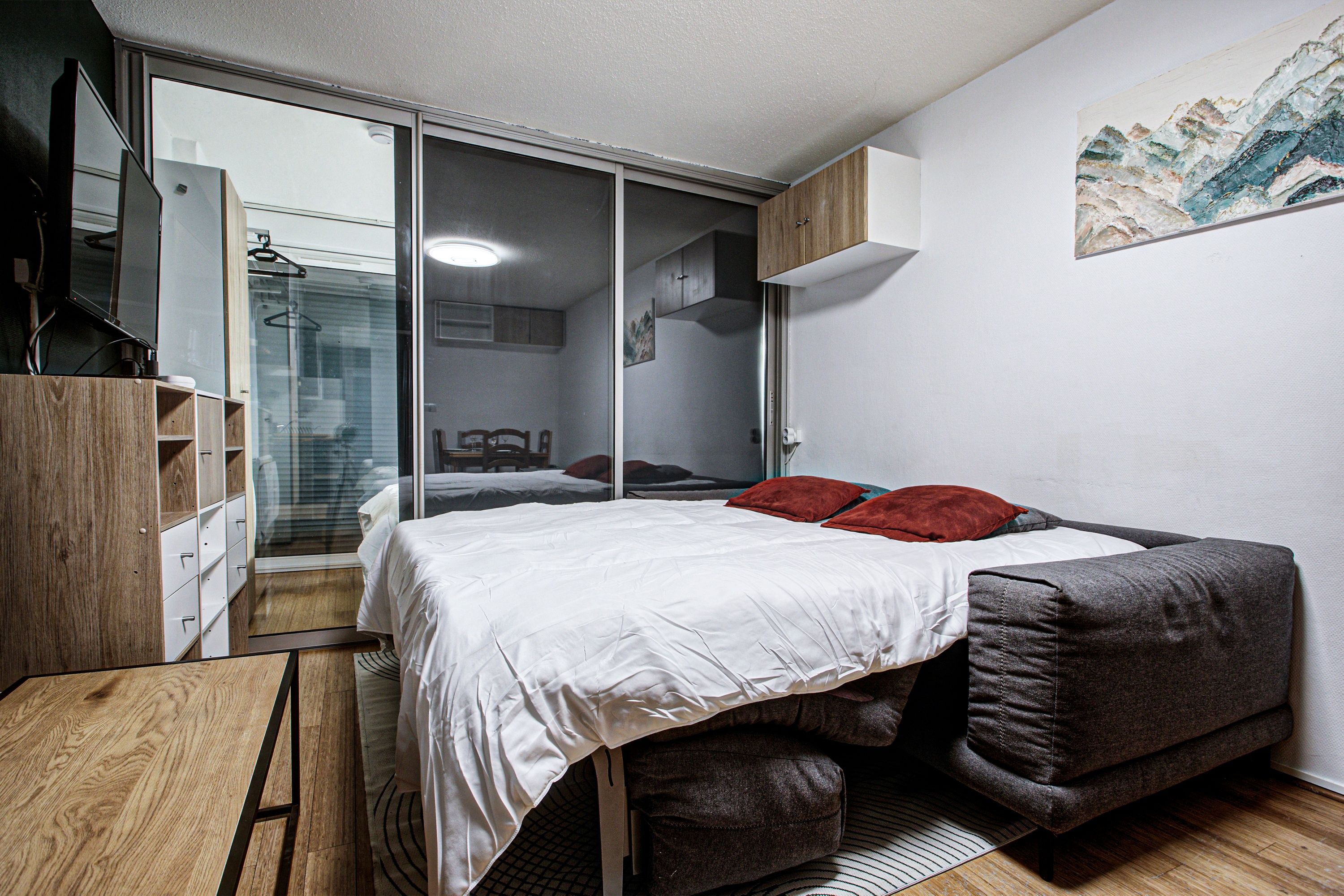 Une chambre à coucher comprenant un lit, une armoire, un bureau et un miroir.