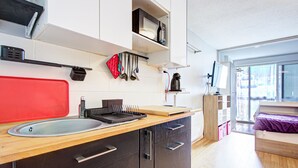Una cocina moderna con encimera de madera, un lavabo y un microondas. Hay una ventana que proporciona luz natural y vistas al exterior.