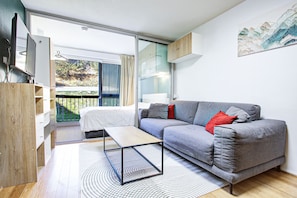 A modern living room with a grey sofa, a small table, and a view of a balcony.