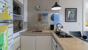 A kitchen with a granite countertop, stainless steel appliances, a kettle, and a water dispenser. - Apto com Vista mar em Canasvieiras Lbm401 (Florianópolis)