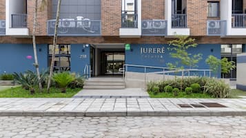 Un edificio moderno con l'indirizzo 258, caratterizzato da un ingresso ben visibile, un balcone con ringhiere e un'area giardino curata.