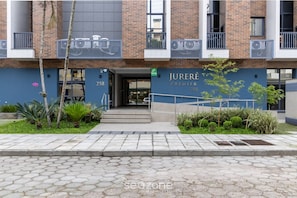 A modern building with the address 258, featuring a prominent entrance, a balcony with railings, and a well-maintained garden area. - Apt w/ Swimming Pool 6min From Jurere Beach Jpr217 (Florianópolis)