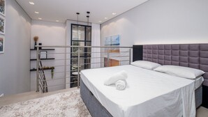Ein modernes Schlafzimmer mit großem Bett, einem Balkon und Blick ins Freie.