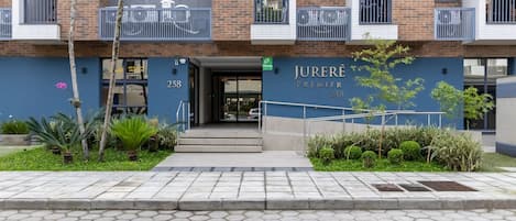 Un edificio moderno con la dirección 258, que presenta una entrada destacada, un balcón con barandillas y un jardín bien cuidado.