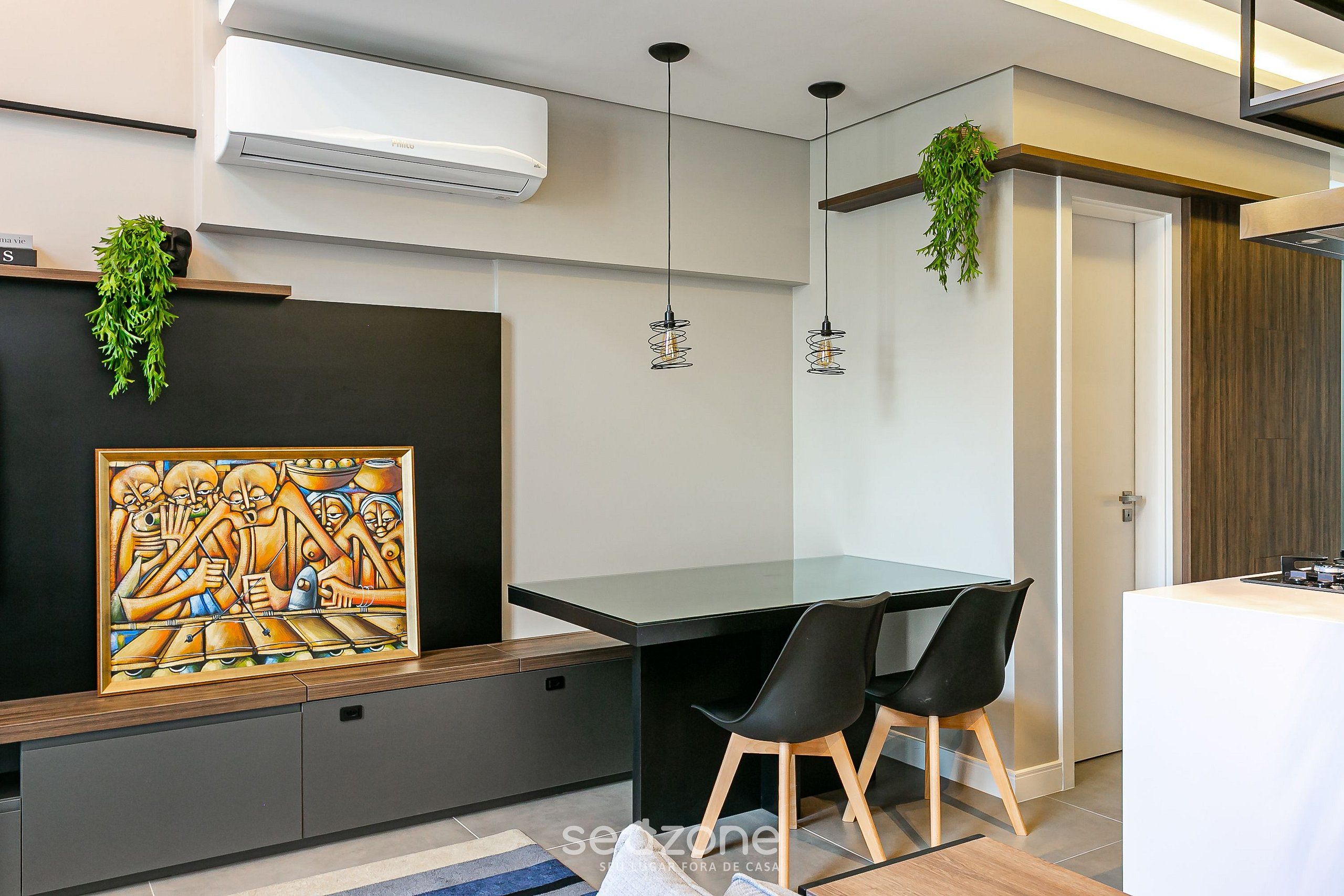 A modern kitchen with a black countertop, two black chairs, and hanging plants.