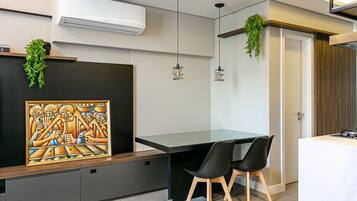 A modern kitchen with a black countertop, two black chairs, and hanging plants.