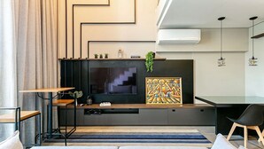 Un salon moderne avec un téléviseur encastré, un tableau décoratif et une petite plante posée sur la cheminée.