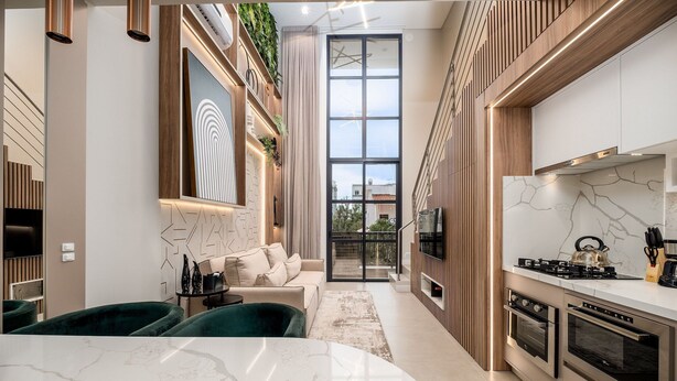 Una cocina moderna con electrodomésticos integrados, un comedor con mesa de mármol y una sala de estar con sofá y sillas verdes.