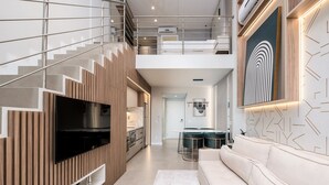 Un interior moderno con una escalera, un televisor de pantalla plana, un sofá y una zona de comedor.