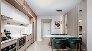Una cocina moderna con electrodomésticos integrados, encimera de mármol y comedor con mesa redonda y sillas verdes.