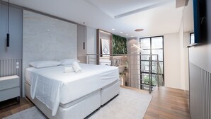Un dormitorio moderno con una cama grande, un armario empotrado, un balcón con vistas y un espejo amplio.
