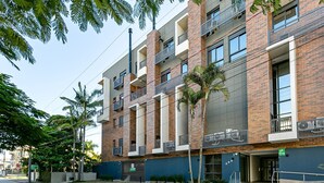 Un edificio de varios pisos con balcones, una entrada con portón y un letrero que indica 'SEU LUGAR FORA DE CASA' (hogar fuera de casa).