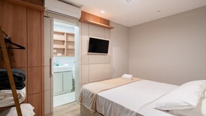 Una habitación de hotel con cama, televisión instalada en la pared, armario y espejo.